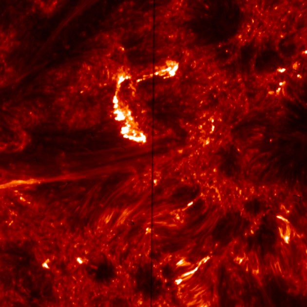 This image from the Interface Region Imaging Spectrograph (IRIS) shows emission from hot plasma in the Sun's transition region-the atmospheric layer between the surface and the outer corona. The bright, C-shaped feature at upper center shows brightening in the footprints of hot coronal loops, which is created by high-energy electrons accelerated by nanoflares. The vertical dark line corresponds to the slit of the spectrograph. The image is color-coded to show light at a wavelength of 1,400 Angstroms. The size of each pixel corresponds to about 120 km (75 miles) on the Sun. (NASA/IRIS image) 