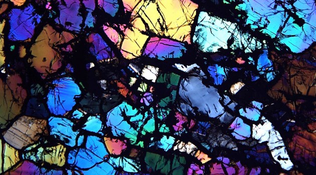 When examined under a microscope with polarized light, ureilite meteorites appear in dazzling colors separated by black bands of graphite and space diamonds. (Smithsonian photo)